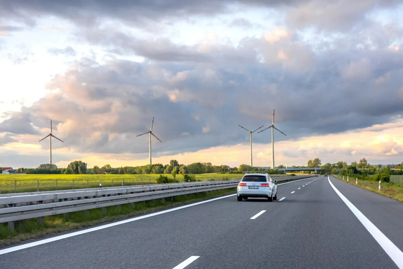 Автомобиль на шоссе, ветроэнергия на шоссе, экологичный транспорт, современный пейзаж.